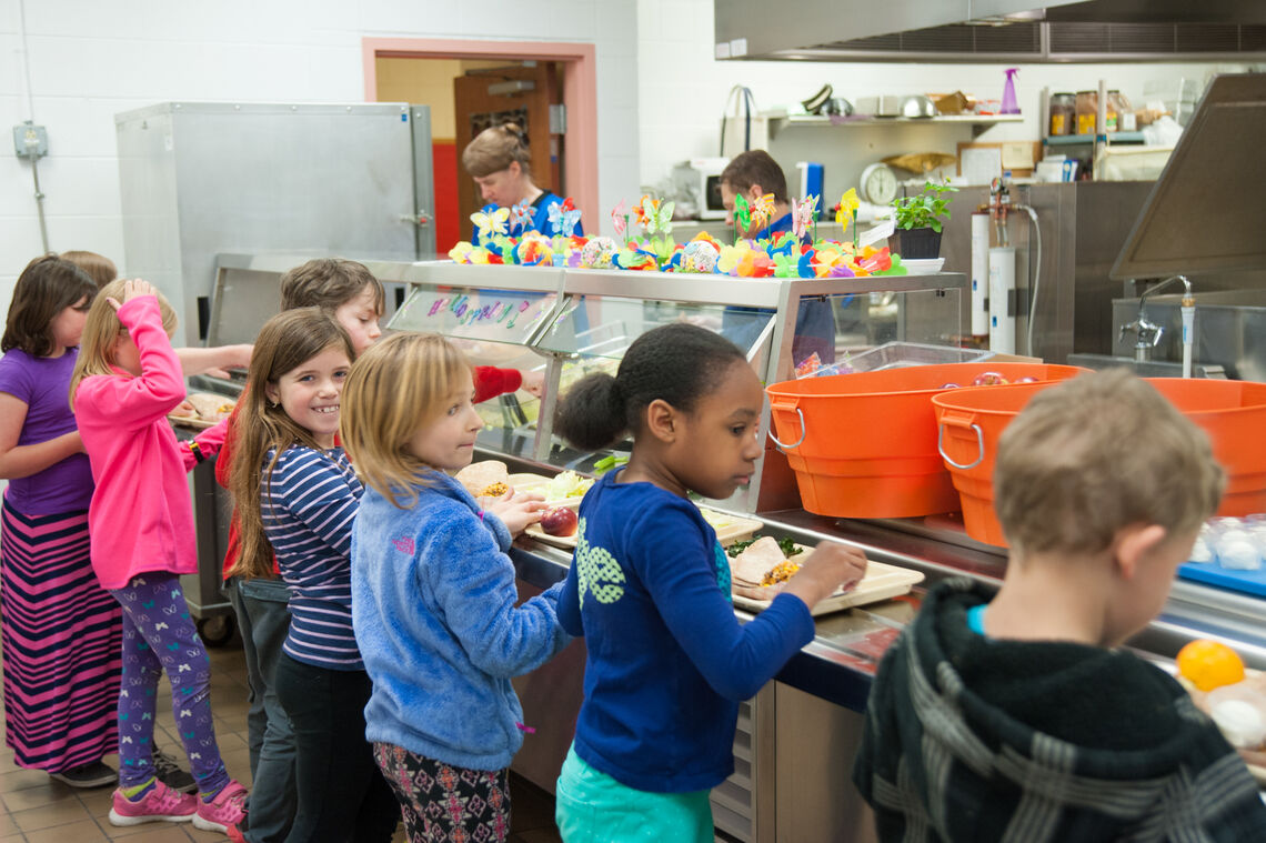 Students lined up at the lunch counter with their trays getting school lunch