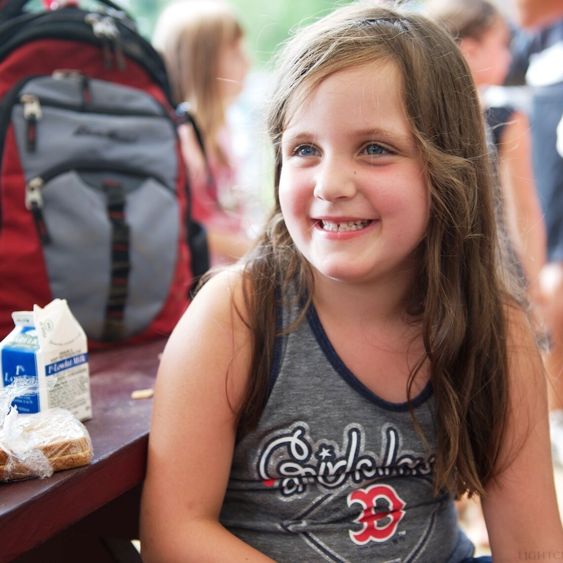 Little girl smiling at a picnic table with lunch at Summer Eats site