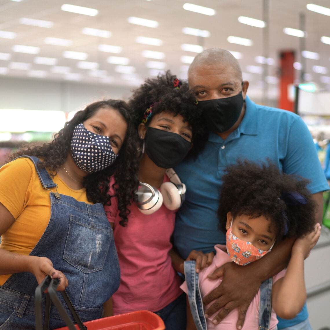 Family with two kids posing for a photo in the grocery store, with masks on