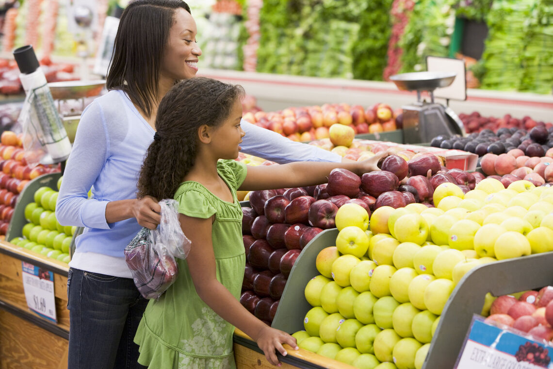 mom and daughter shopping for produce in grocery store