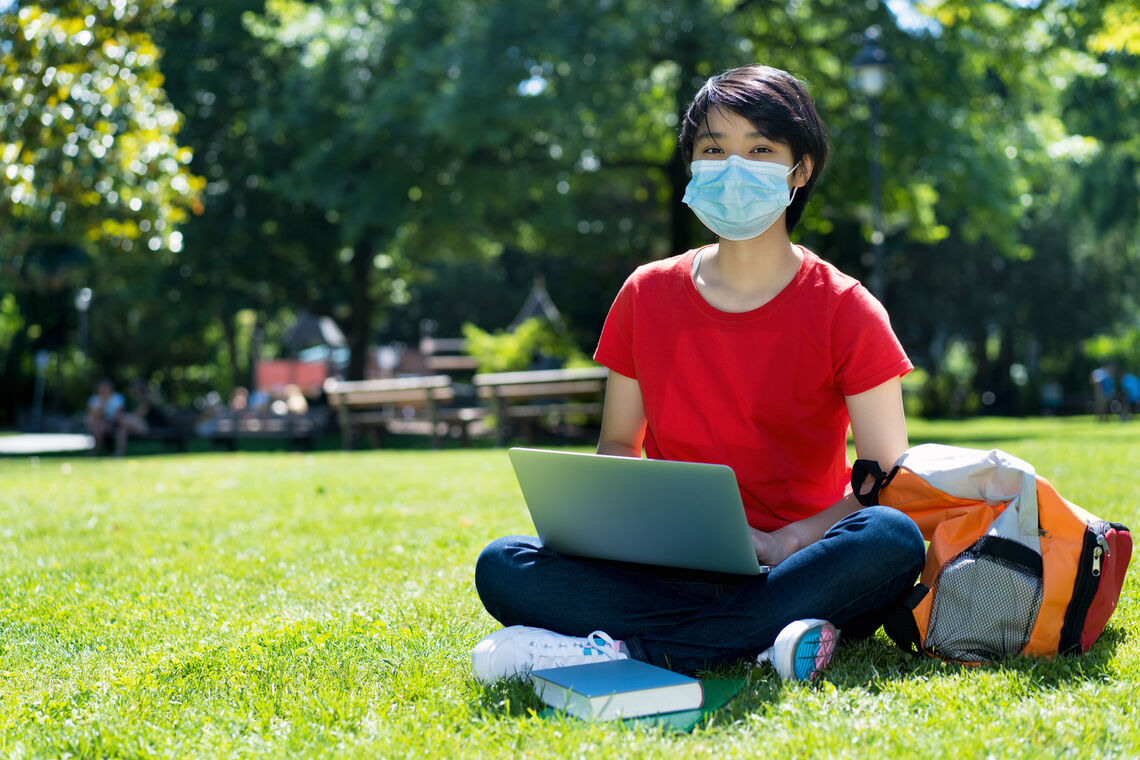 East Asian male student with face mask at campus of university in summer