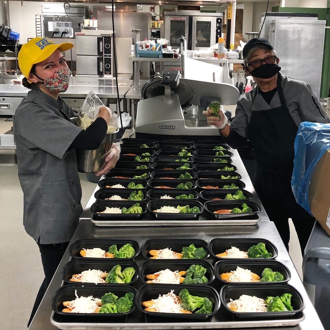 Two school nutrition professionals working hard to prepare school meals for kids through pandemic