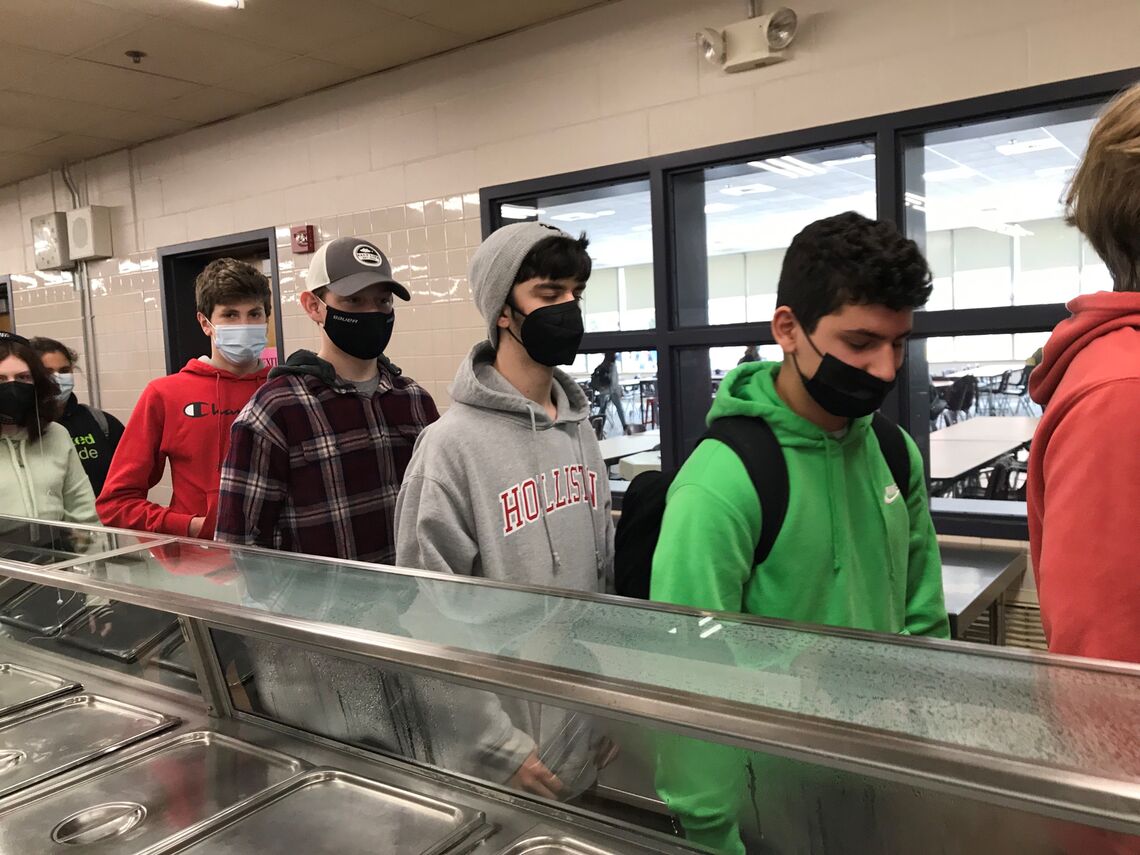 A line high school teens lineup for school breakfast , wearing face masks