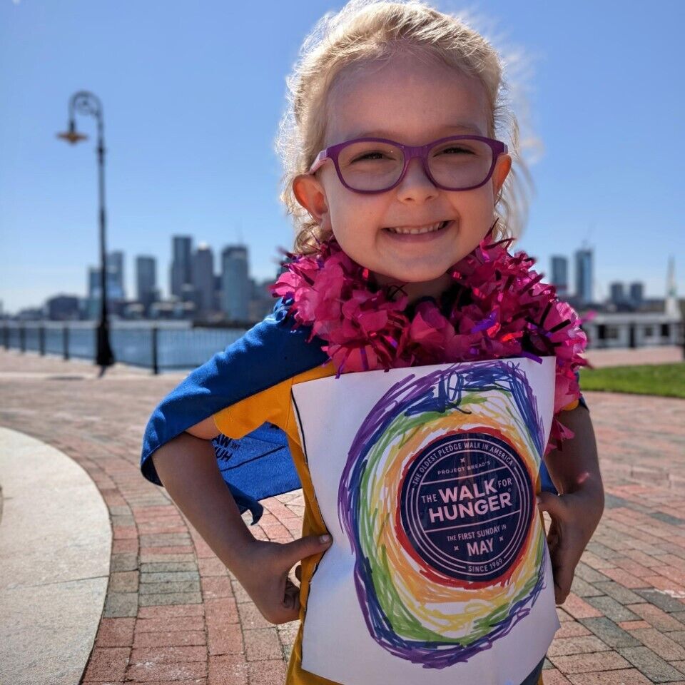 Little girl with glasses beams while wearing a Walk for Hunger bandana as a cape