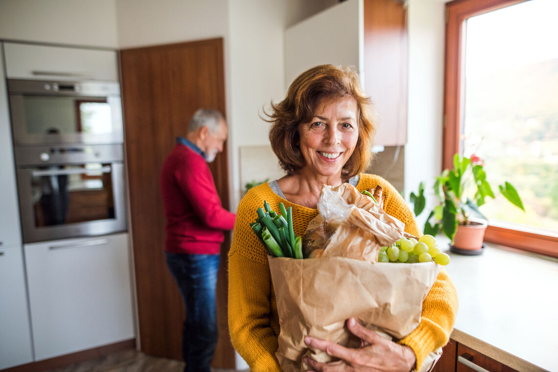 Woman smiling and holding bag of groceries
