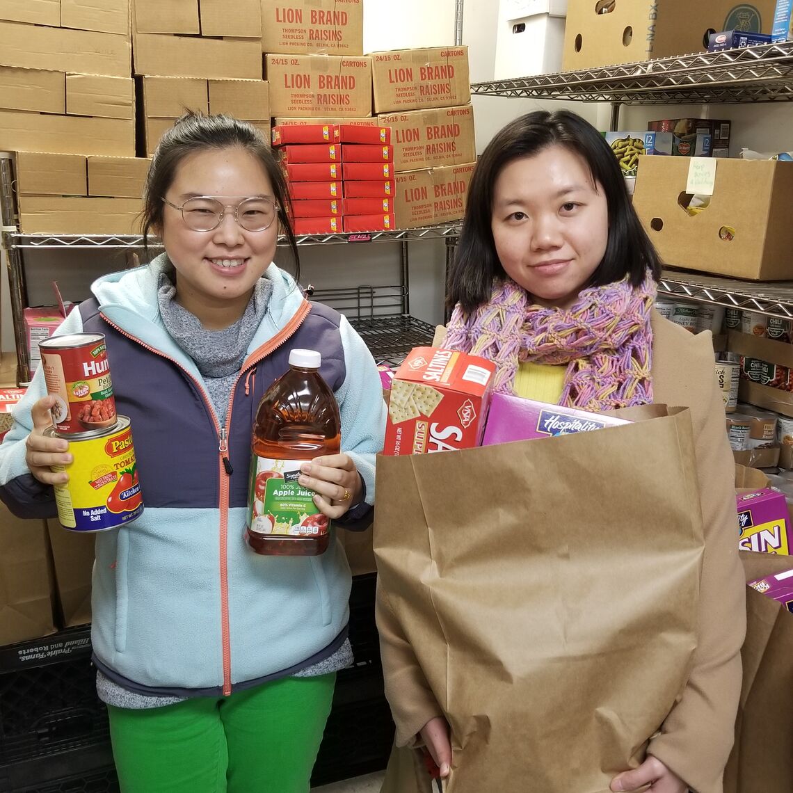 Daisy and Summer standing in food pantry holding food items