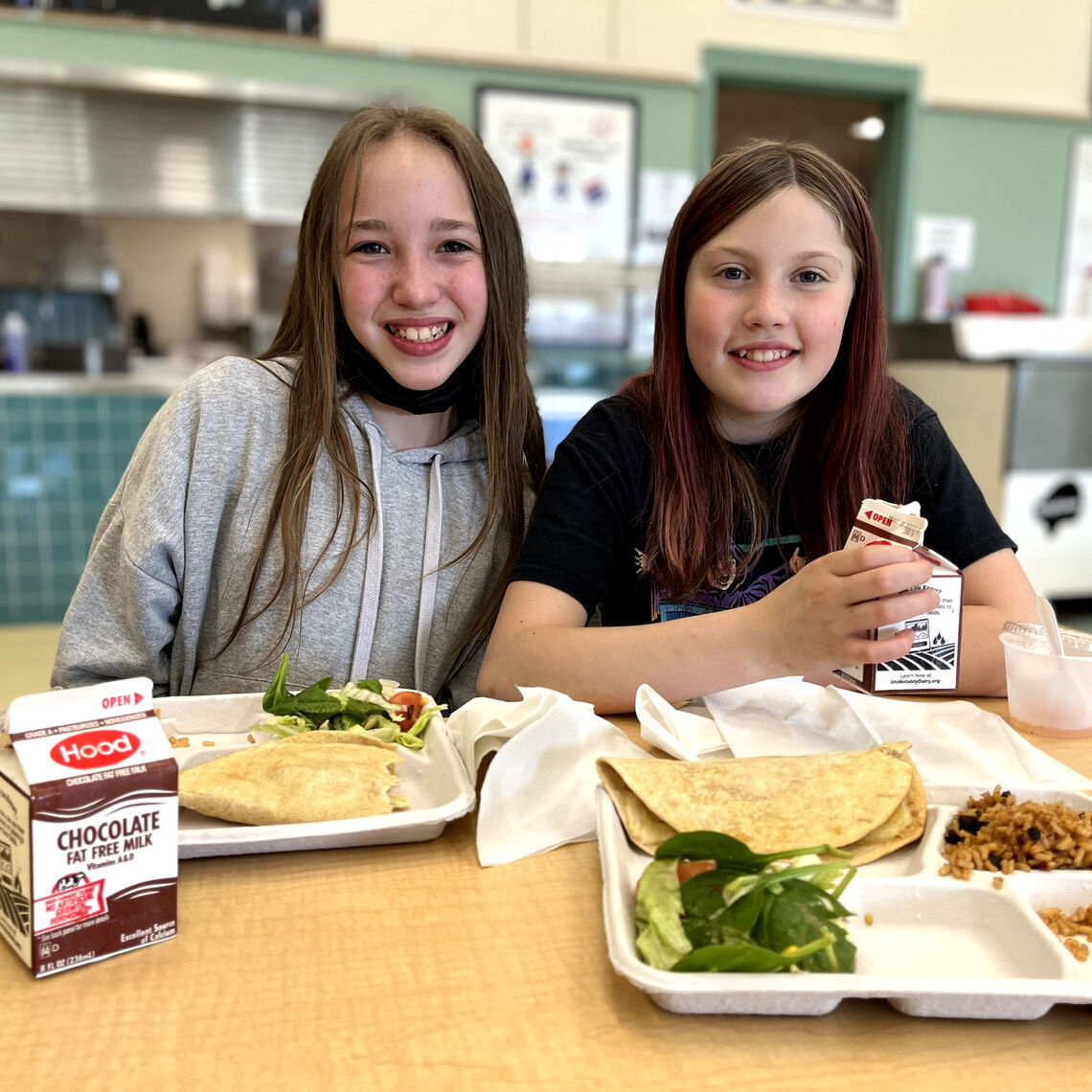 two girls eat school lunch in the cafeteria