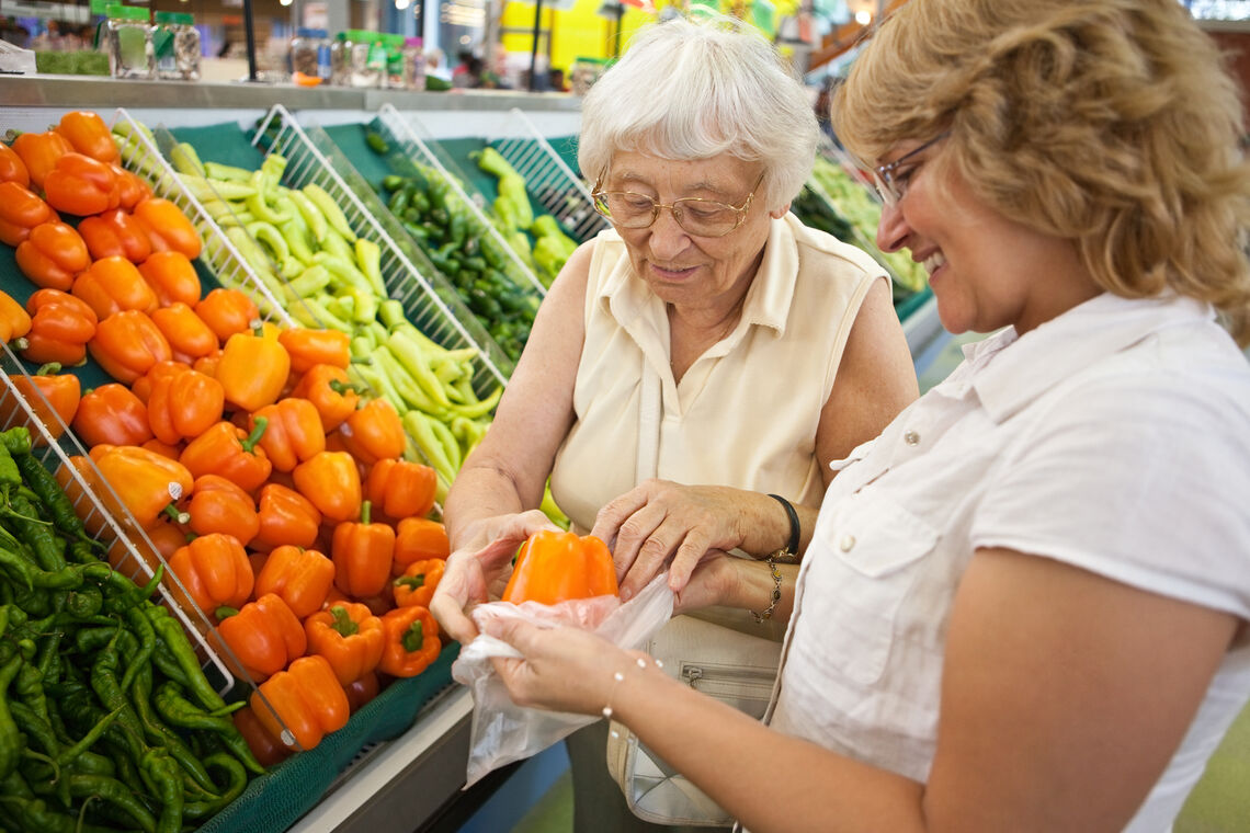 two woman bagging a pepper in grocery store